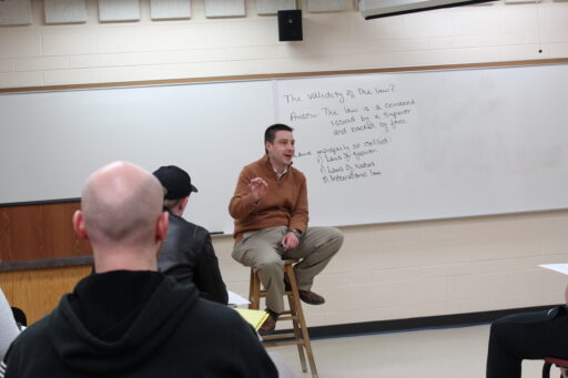 Professor Horn sits on stool in course discussion with students