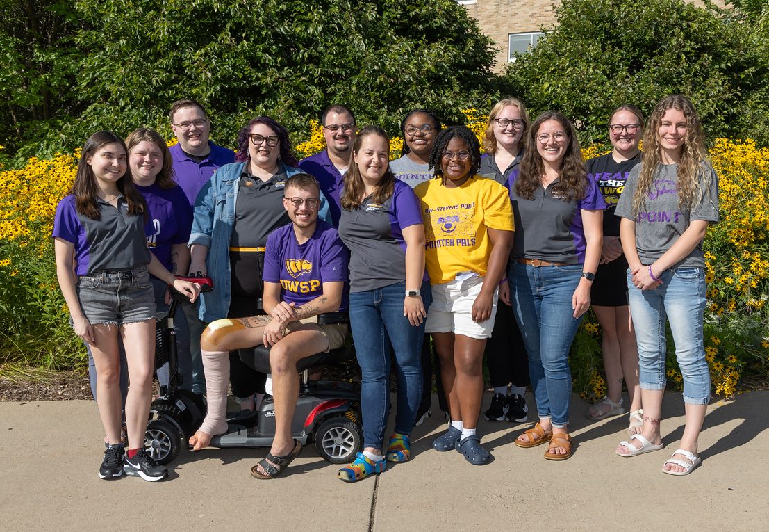 Hall Director Team posed as a group outside in front of yellow flowers. They all look happy and excited to start their year.