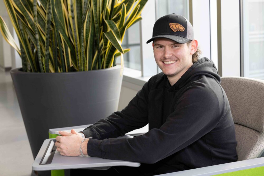 Male student smiling and sitting in a chair in the Chemistry Biology Building.